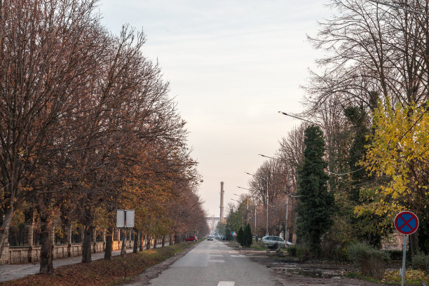 在一个寒冷的秋日，在塞尔维亚潘切沃，一个废弃的工业工厂复合体和它典型的高大的红砖烟囱在公园大街前的全景。图片下载