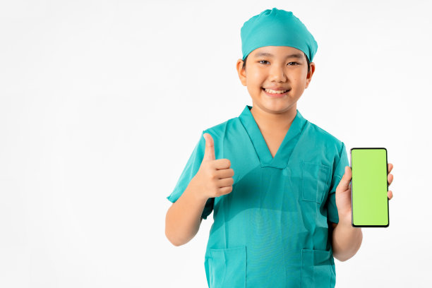年轻的亚洲男孩的肖像打扮成医生，拿着智能手机与绿色屏幕隔离在白色背景，教育和技术概念图片下载