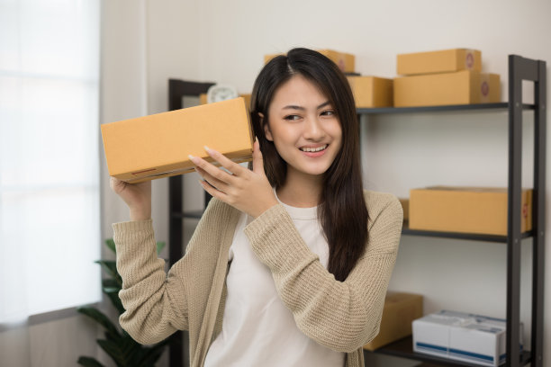 美丽年轻的亚洲企业家站姿。女性小企业主与盒子工作在家里。有很多背景的创业自由职业者。图片下载