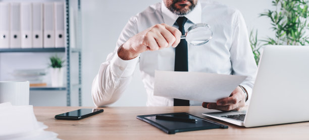 税务稽查员和财务审计员透过放大镜检查财务文件图片下载