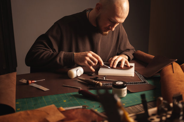 英俊的鞣皮男人在工作的肖像，手工生产，小企业，真实的车间，室内。用自己的双手，做皮具。使钱包图片下载