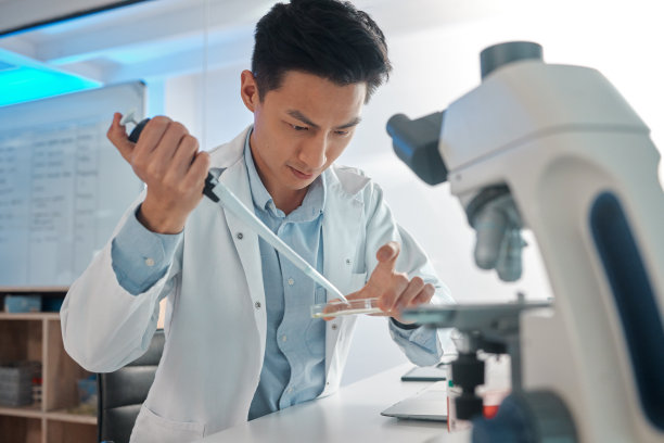一名男性实验室技术人员在显微镜下填充培养皿的照片图片下载