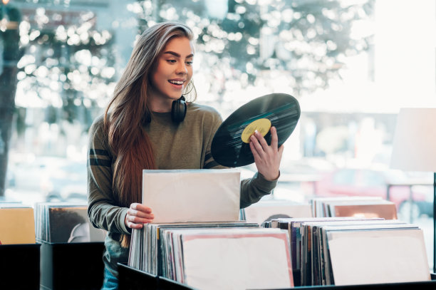 一个女人拿着黑胶唱片在音乐店里挑选唱片。图片下载