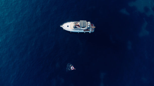 在亚得里亚海游艇附近的蓝色海水中，鸟瞰苗条女子游泳圈。夏天的海景女孩，美丽的波浪，蓝色的水在阳光明媚的日子。俯视图从无人机图片下载