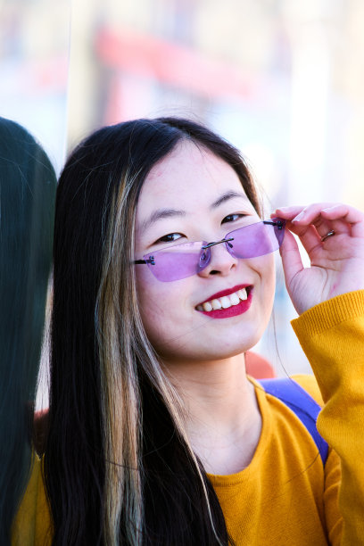 年轻女子的肖像，拿着她的紫色眼镜看着相机图片下载