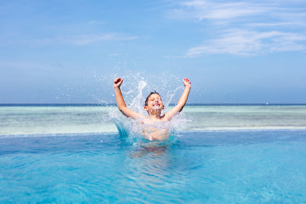 一个有趣的孩子跳进了一个无边际的游泳池图片下载