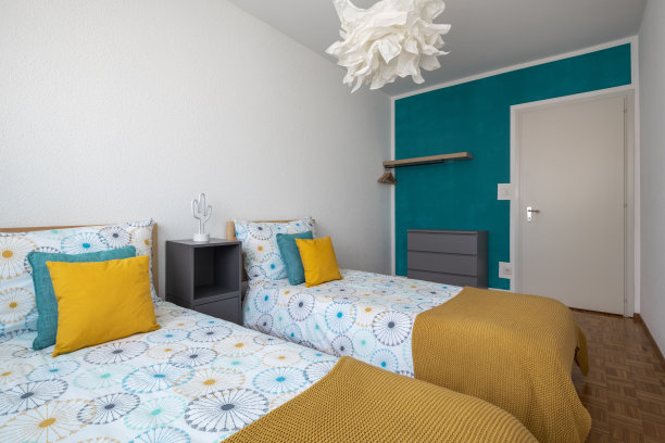 宽敞的房间为儿童提供两张单人床，彩色床单和许多枕头图片下载