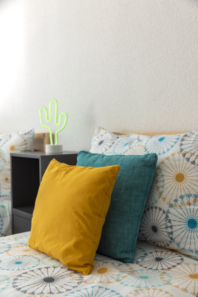 床上有彩色床单和配套的黄色和绿松石色靠垫图片下载