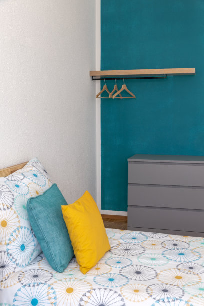 床上有彩色床单和配套的黄色和绿松石色靠垫图片下载