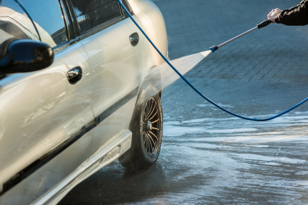 一名男子在自助洗车店用喷水器洗车，特写镜头图片下载