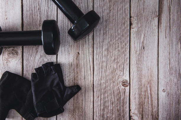 木制背景的健身哑铃和运动手套。健身配件。副本的空间。有选择性的重点。图片下载