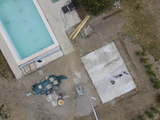 游泳池施工现场，热泵混凝土垫块和花园中的游泳池房的无人机拍摄图片下载