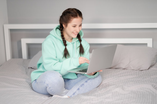 远程工作或在家远程学习。年轻的黑发女人女孩在床上与笔记本电脑。检疫限制。covid-19大流行图片下载