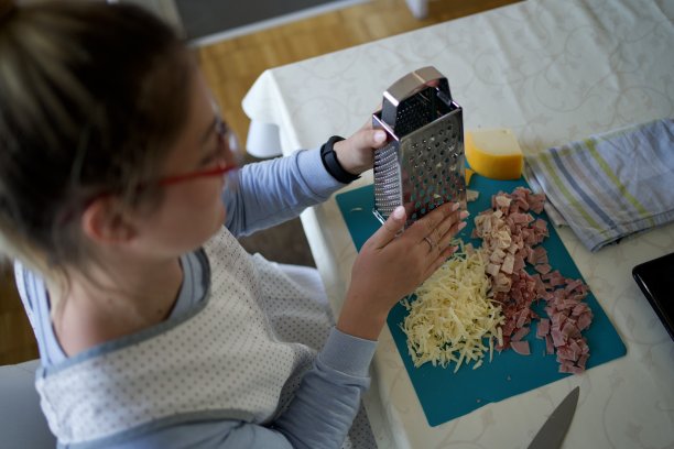 年轻的女性正在刨奶酪，准备披萨图片下载