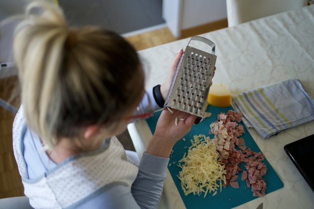 年轻女孩，美食博主，在厨房里磨奶酪图片下载