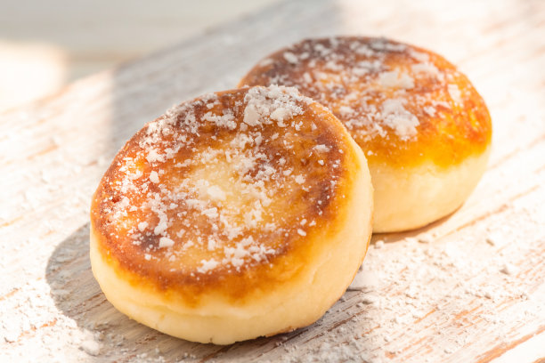 阳光下，两块奶酪蛋糕放在一块老旧的木板上。食物的照片。图片下载