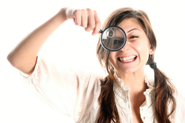 微笑的女人(女孩)拿着放大镜看着-侦探图片下载