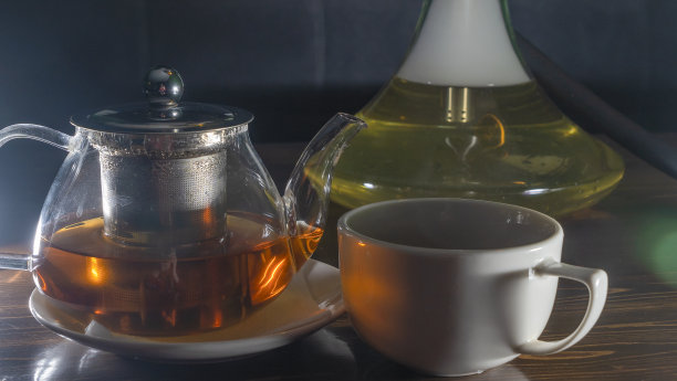 图片玻璃茶壶与陶瓷杯绿茶在黑暗的背景。热的中国绿茶。图片下载