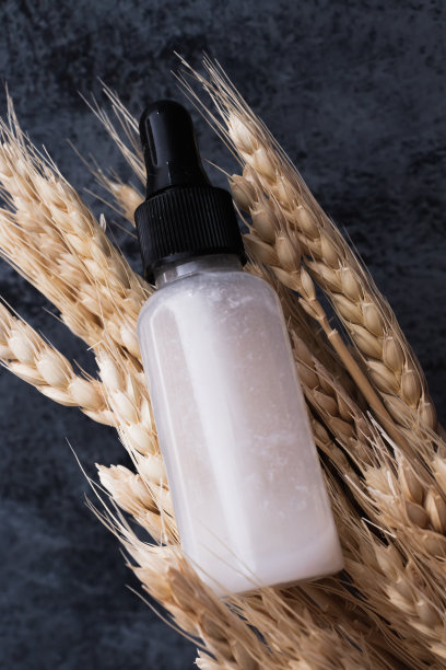 来自植物的天然有机化妆品，用于皮肤护理。面部精华液滴管玻璃瓶和干麦穗树皮背景。垂直照片，特写，海报。图片下载