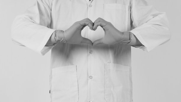 医生用听诊器做爱的手势。手戴蓝色医用手套，身穿白底长袖长袍。黑白图片图片下载