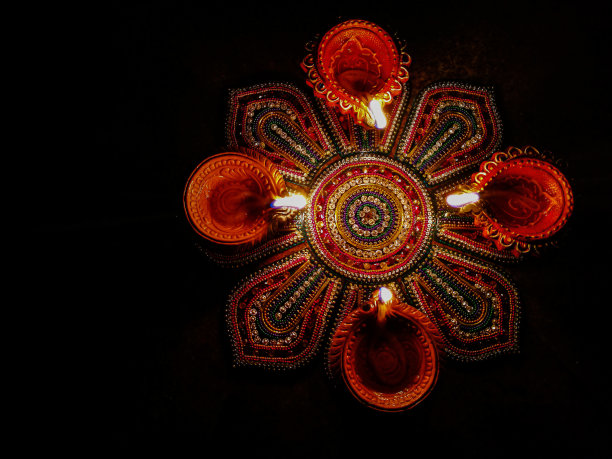 美丽的粘土油灯的照片，尤其是在排灯节期间，在黑暗的背景下保持彩色的rangoli。图片拍摄于印度卡纳塔克邦的班加罗尔。专注于灯图片下载