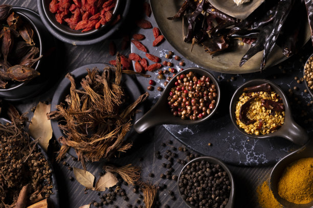 在深色木桌上放上各种具有东方泥土风味的干香料，如姜黄，黑胡椒，辣椒片，月桂叶，用于医药和草药治疗和烹饪图片下载