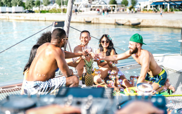 潮流朋友在帆船派对上畅饮美酒-多种族人在帆船上的友谊旅行生活理念-奢华心情在户外享受快乐假期-明亮生动的滤镜图片下载