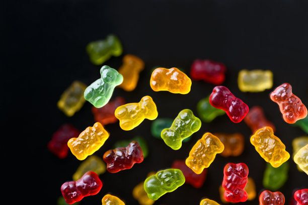 彩色飞行小熊软糖在一个黑色的背景，平躺图片下载