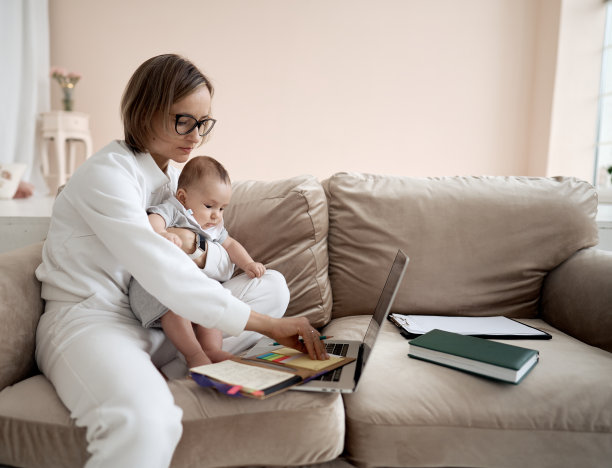 年轻的妈妈在笔记本电脑上工作。女商人在家和小女孩一起工作。在产假期间工作。新型冠状病毒肺炎图片下载