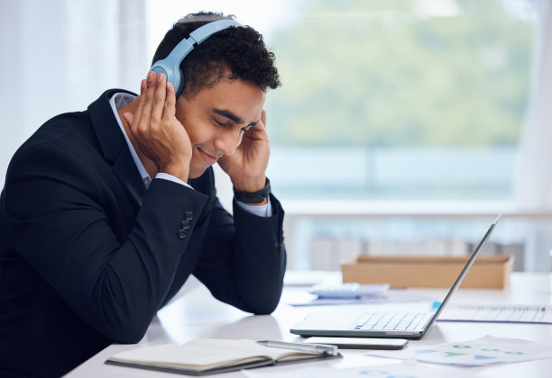 一个年轻的商人戴着耳机在办公室工作的照片图片下载