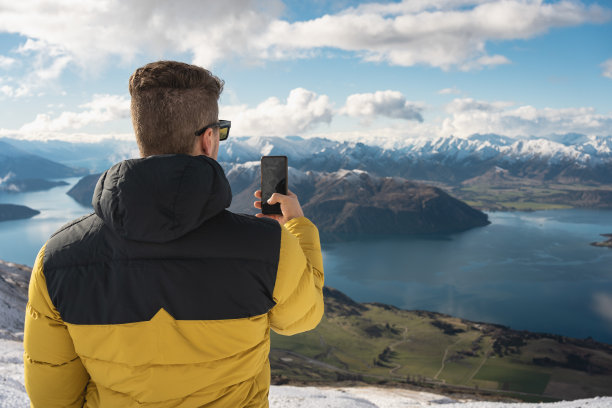 一名白人男子在新西兰瓦纳卡罗伊峰的南阿尔卑斯山用手机拍照图片下载