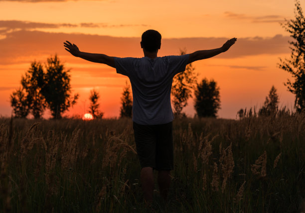 自由的概念。一个人伸开双臂望着夕阳图片下载