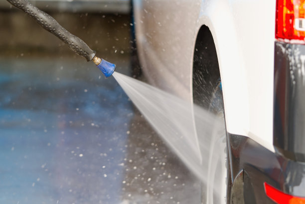 男子在自助洗衣站用压力清洗机清洗他的汽车。图片下载