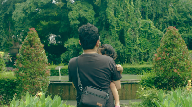 一个男孩和他的女儿在一个绿色的公园里拍了一张背面的照片图片下载