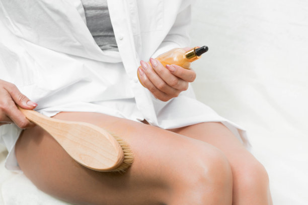 美容、美容、脱皮、水疗美容产品、美容及比基尼概念。白衣女人用木制的按摩刷为身体和脚做脚部按摩。图片下载
