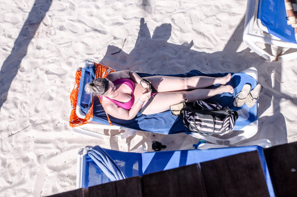 从上面看到沙滩上坐在长椅子上的女人图片下载