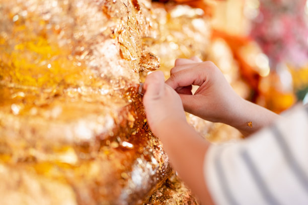 信徒和儿子的手把金箔放在佛祖的背上，这是佛教的传统之一图片下载