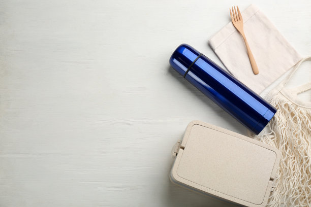 保温瓶和午餐盒在白色木制背景，平躺。空间的文本图片下载