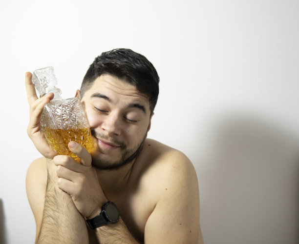 一个男人抱着一瓶威士忌在白色背景下的照片。图片下载