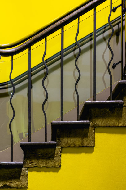 侧面有明亮的黄色装饰楼梯，有锻铁栏杆和木制栏杆图片下载