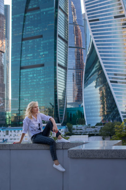 美丽自信的女孩在商业中心的背景下摩天大楼的办公楼图片下载