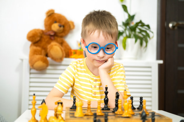 一个白人小男孩在家下象棋。全纳教育理念与早期发展。图片下载