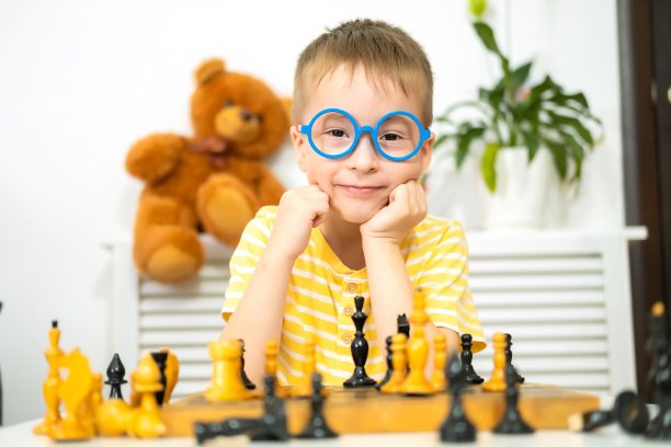 一个白人小男孩在家下象棋。全纳教育理念与早期发展。图片下载