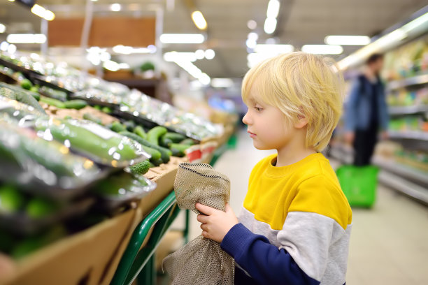 可爱的小男孩在食品店或超市挑选新鲜的有机黄瓜。给孩子们的健康蔬菜。购物与孩子。图片下载