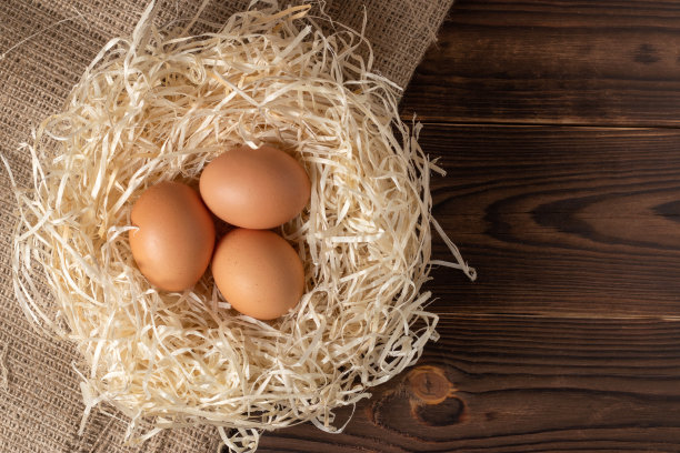 干草和鸡蛋在木制背景上。图片下载