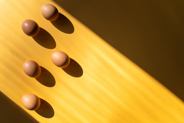 一组新鲜的鸡蛋在桌子上孤立在黄色的背景上。图片下载