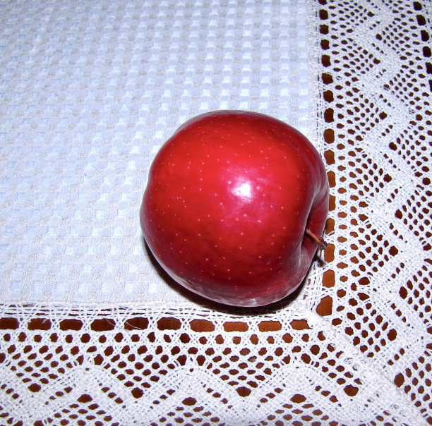 红色的苹果放在有花边的白色亚麻桌布上图片下载