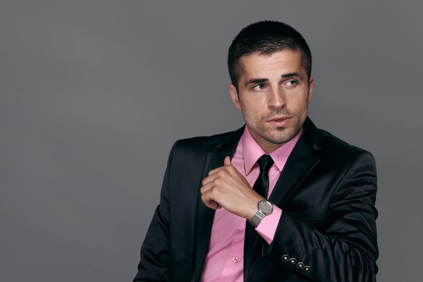 男人穿着黑色西装，戴着手表，半身肖像，工作室时尚肖像。图片下载