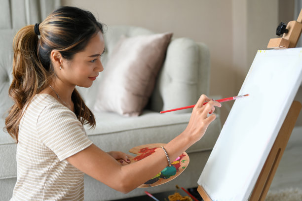 女性在空白的画布画架上画她的创作艺术品。图片下载