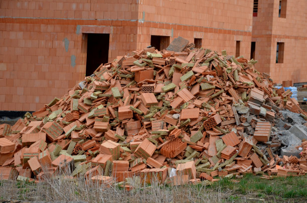 瓦砾堆现代绝缘砖。背景中的房子正在建设中。建筑危机即将来临。石匠们把建筑物的残骸扔在草地上图片下载